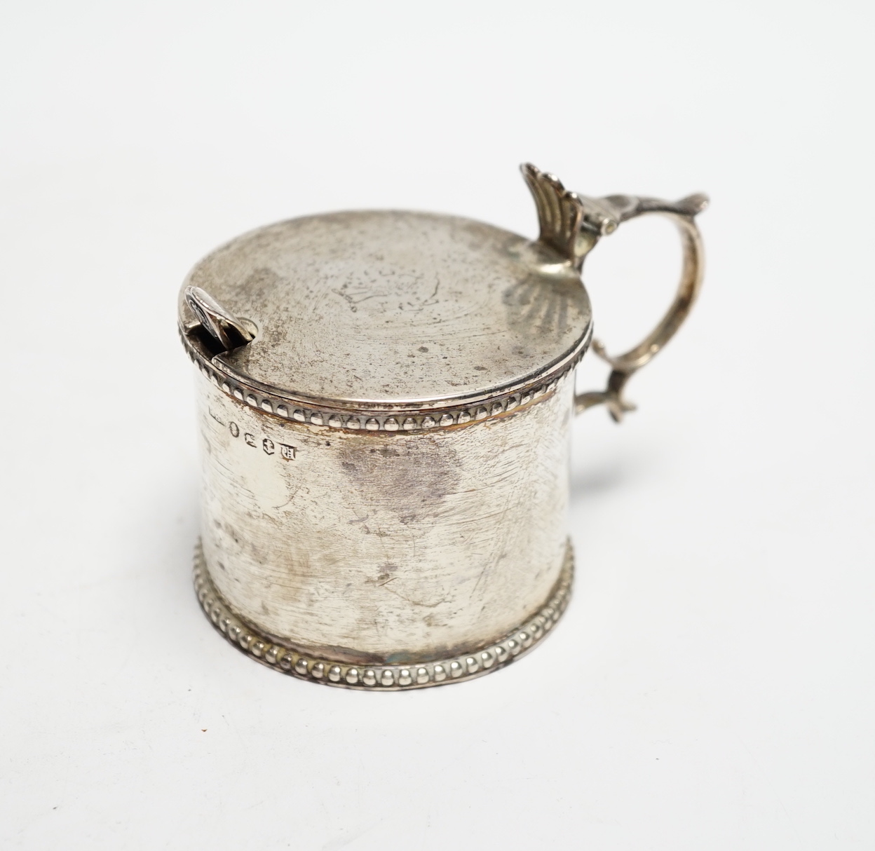 An early Victorian silver drum mustard, maker's mark rubbed, Birmingham, 1843, height 75mm, with two associated spoons, one silver.